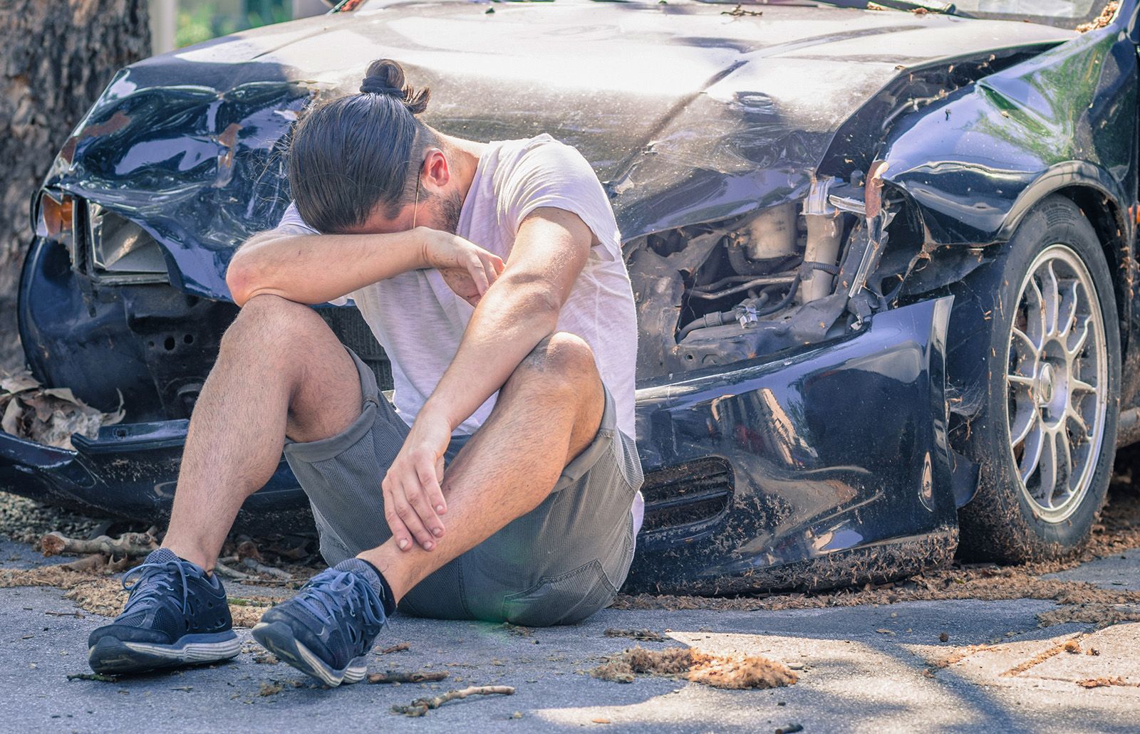 Upset man in front of wrecked car